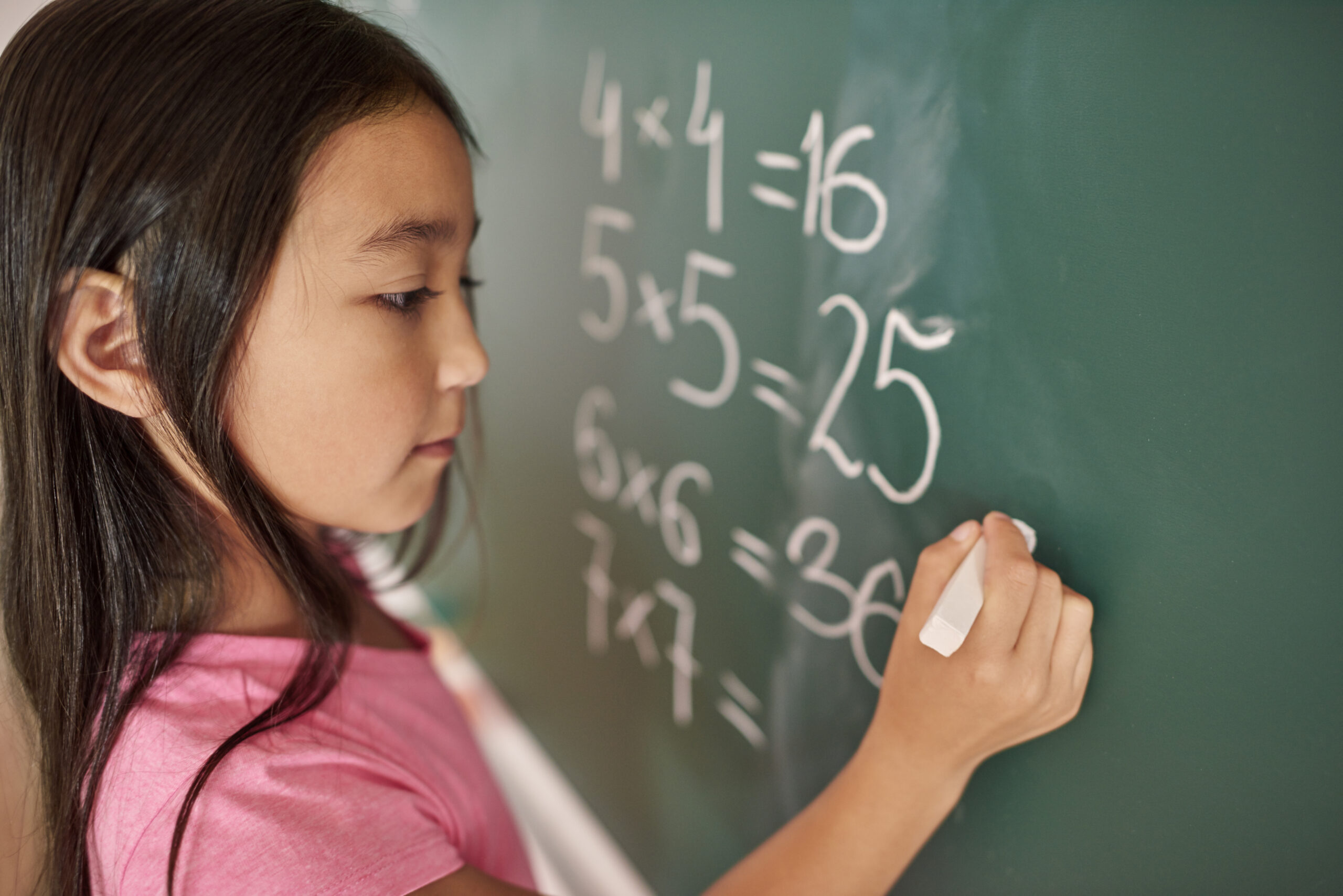Criança focada resolvendo matemática na lousa